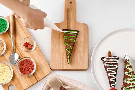 Festive Christmas cookies being decorated with colorful icing on a wooden board.