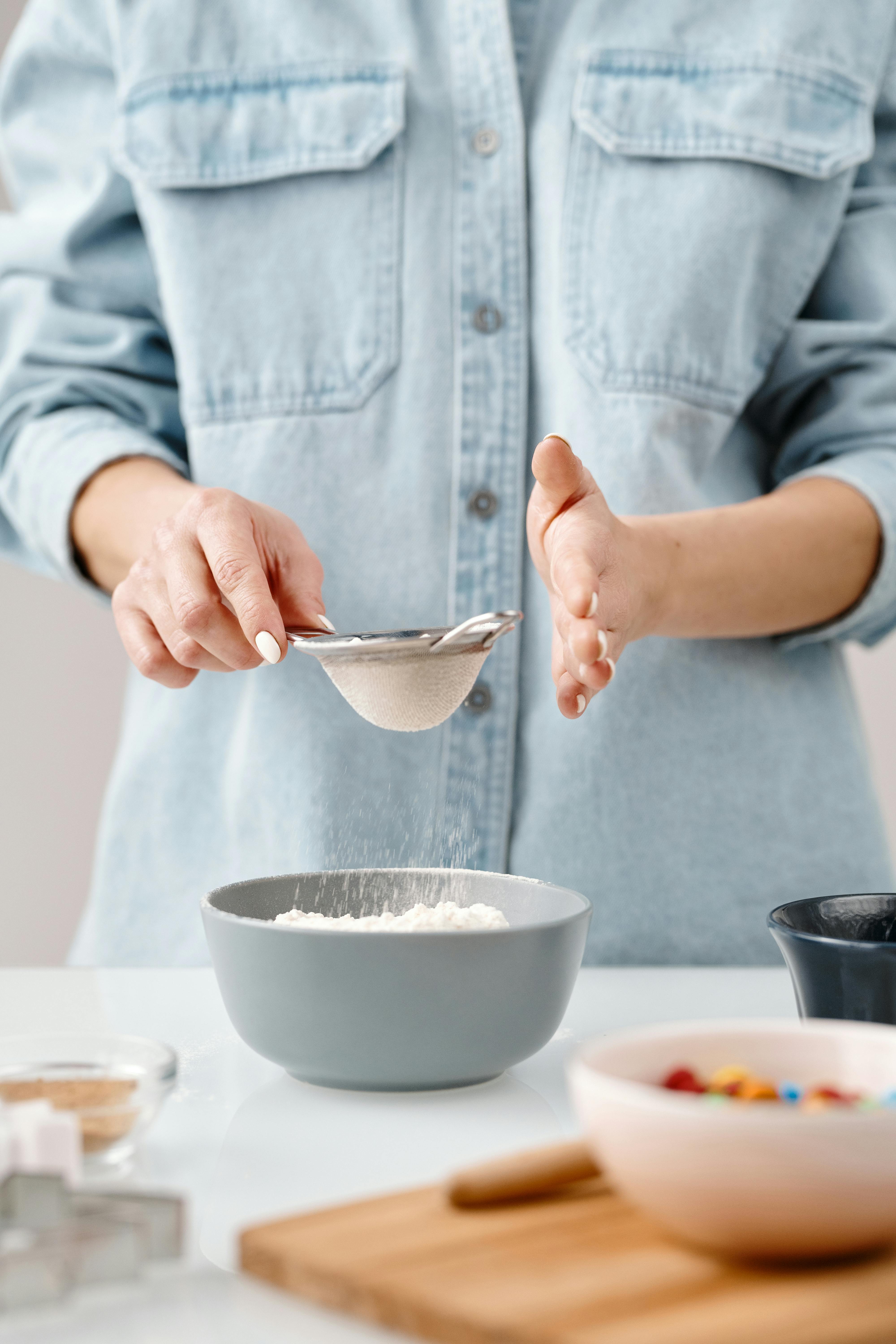 person holding stainless strainer with white powder