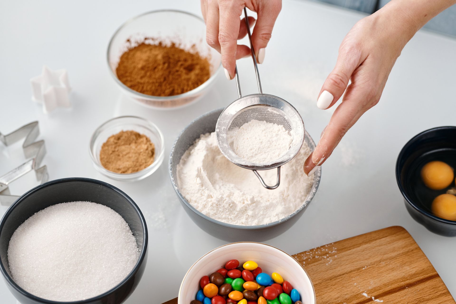 Overhead view of baking ingredients and tools in a festive setting with hands at work.