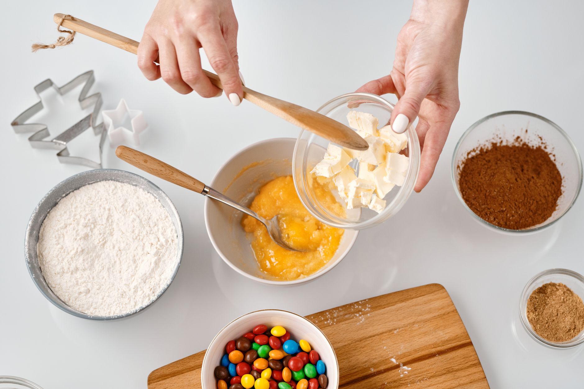 Decadent Chocolate Tahini Cookies in One Bowl A person preparing ingredients for baking with a variety of bowls and colorful candies.