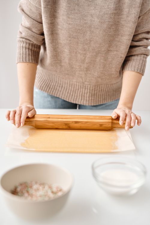 Free Person rolling dough for homemade cookies with bowls in a festive kitchen. Stock Photo