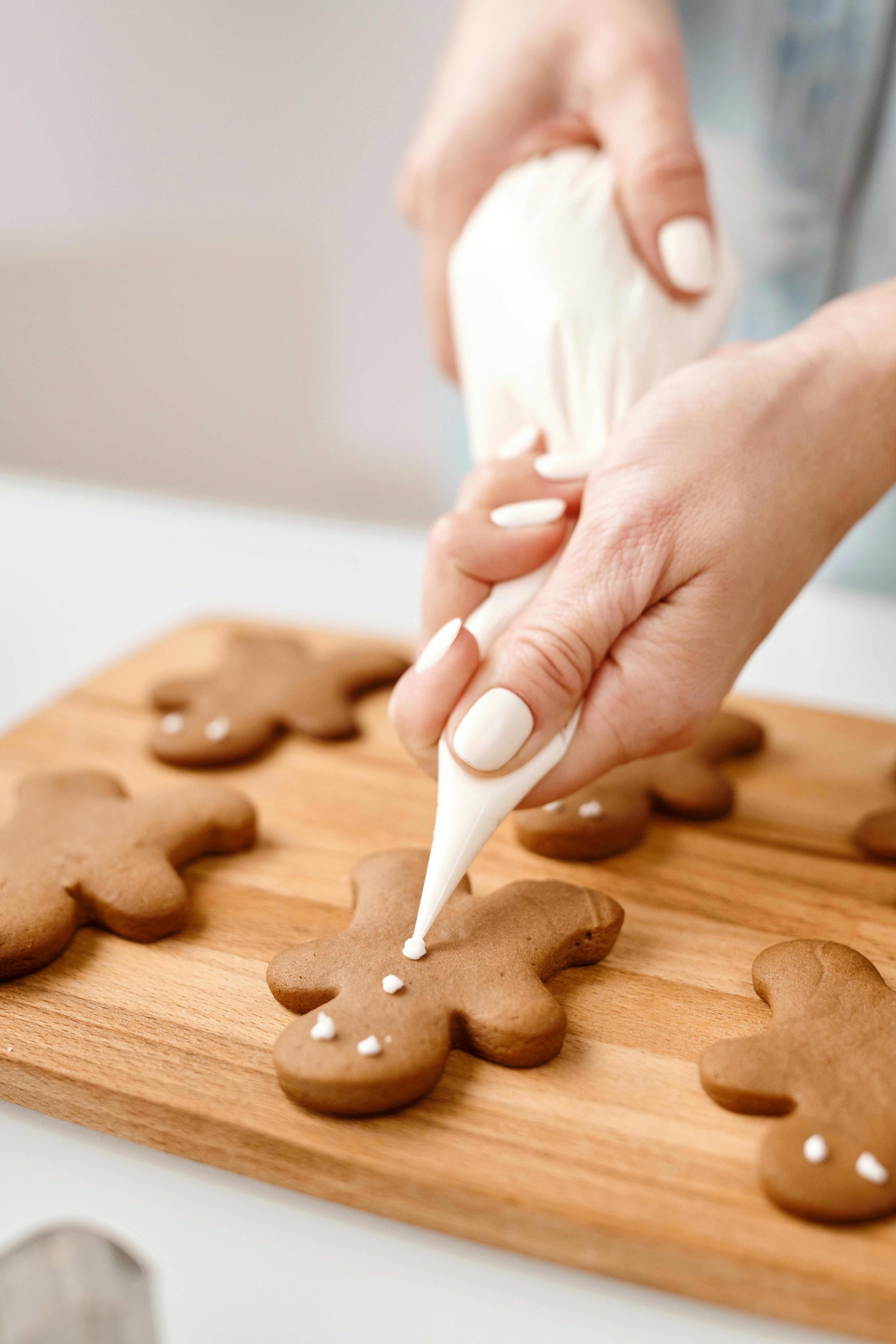 person decorating a gingerbread man cookies