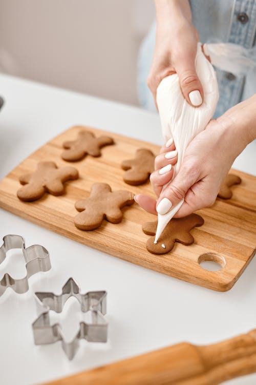 Person Decorating a Gingerbread Man Cookies