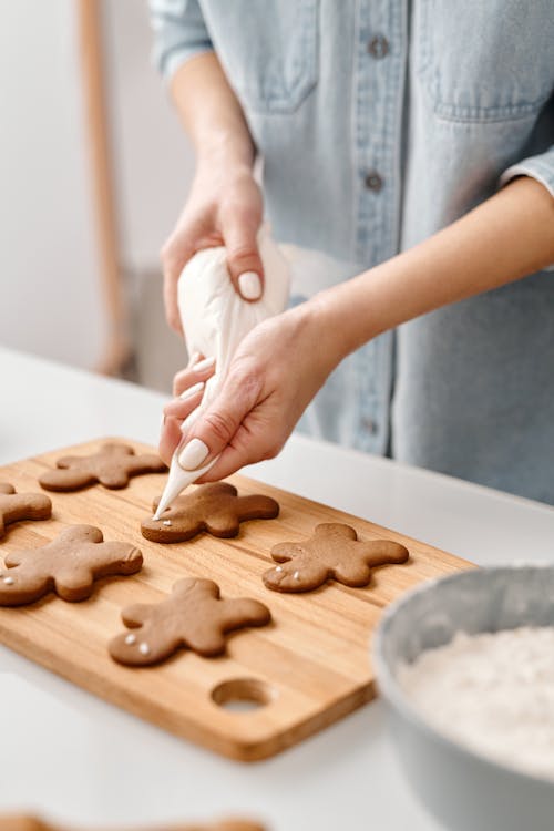 Person Decorating a Gingerbread Man Cookies