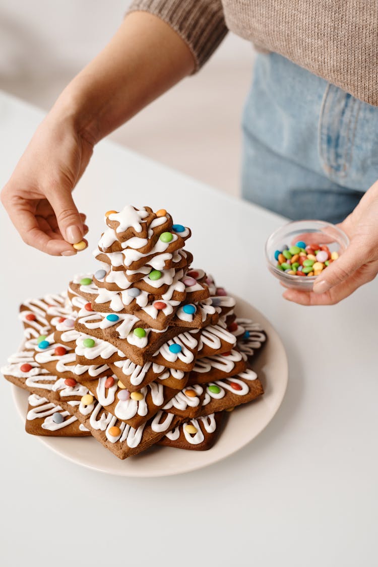 Person Decorating A Stack Of Brown Cookies