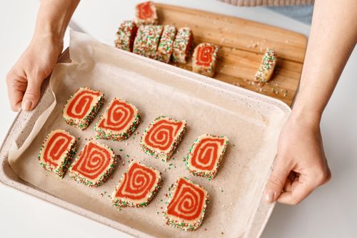 Free Colorful spiral cookies with sprinkles on a baking tray, perfect for festive occasions. Stock Photo