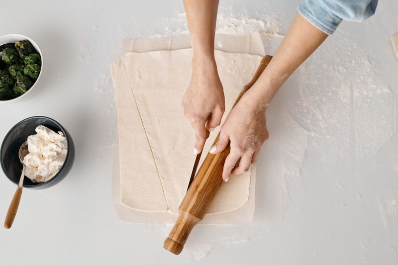 Preparing dough with a rolling pin in a modern kitchen, featuring fresh ingredients and a minimalist style.