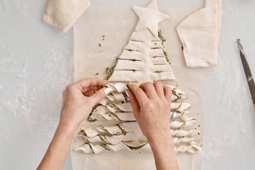 Hands crafting a festive tree-shaped pastry with filling, ideal for Christmas baking.