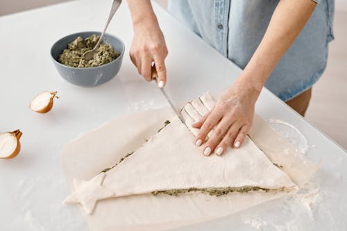 Person Slicing a Christmas Tree Shaped Bread With Fillings