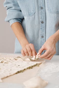 Close-up of a woman shaping pastry dough, highlighting hands-on preparation in a cozy kitchen setting.