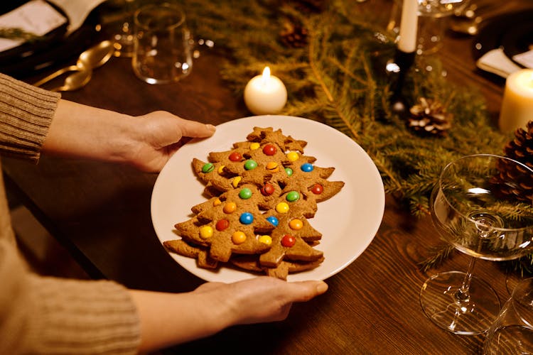 Person Serving A Platter Of Christmas Tree Shaped Cookies