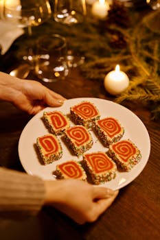 Plate of spiral Christmas cookies with colorful sprinkles, set on a wooden table surrounded by holiday decor.