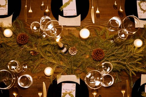 Free Top view of a festive Christmas dinner setup with candles and pine decor, capturing a warm, elegant atmosphere. Stock Photo
