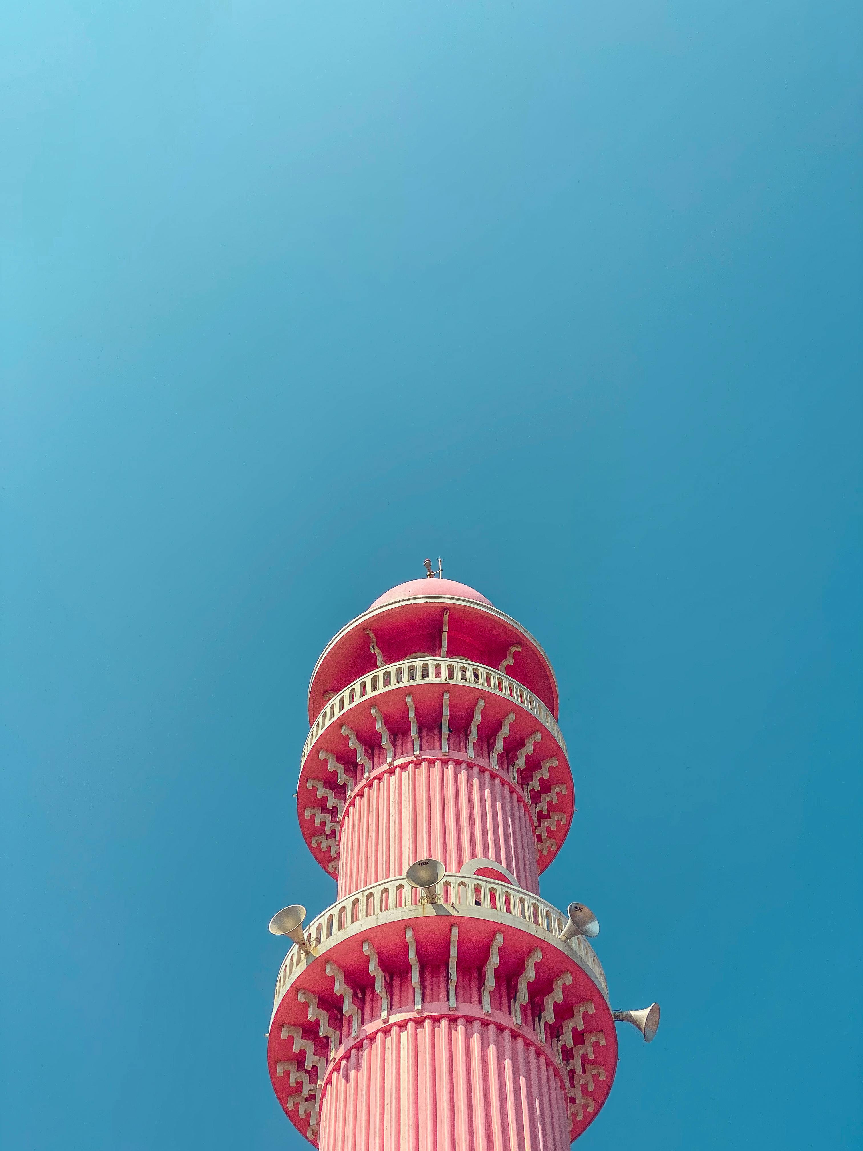 A striking pink minaret set against a clear blue sky in Thiruvananthapuram, India.