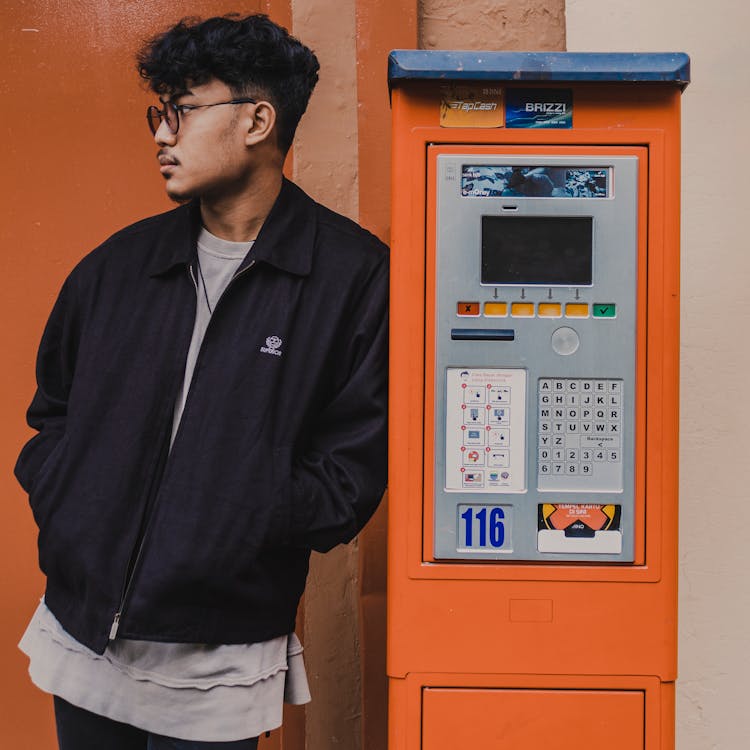 Ethnic Man Leaning On Payment Kiosk