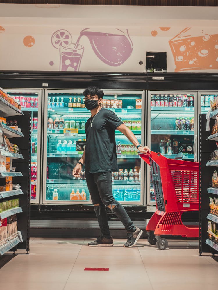 Man With Trolley Walking Near Fridge In Supermarket