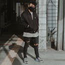 Stylish man in mask standing near shabby building