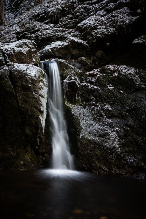Free A tranquil waterfall cascades over mossy rocks in a peaceful natural setting. Stock Photo