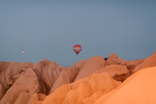 Free Picturesque view of hot air balloons flying over rocky chimneys with smooth surface in Cappadocia on early morning Stock Photo