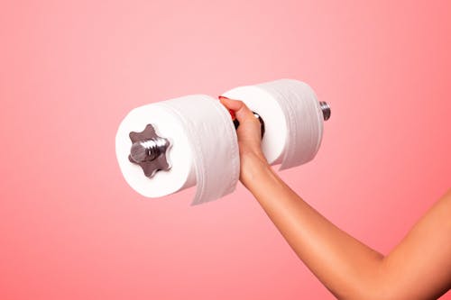 Белый рулон туалетной бумаги на розовой поверхности