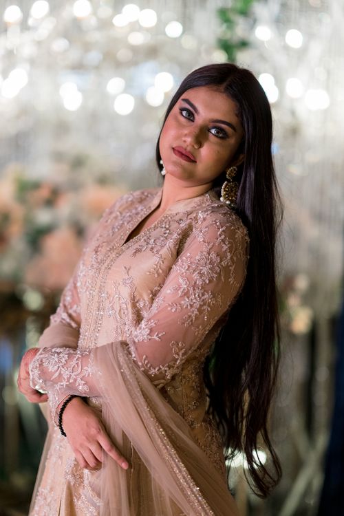 Free Elegant bride in traditional attire with intricate embroidery, posed amid sparkling lights. Stock Photo