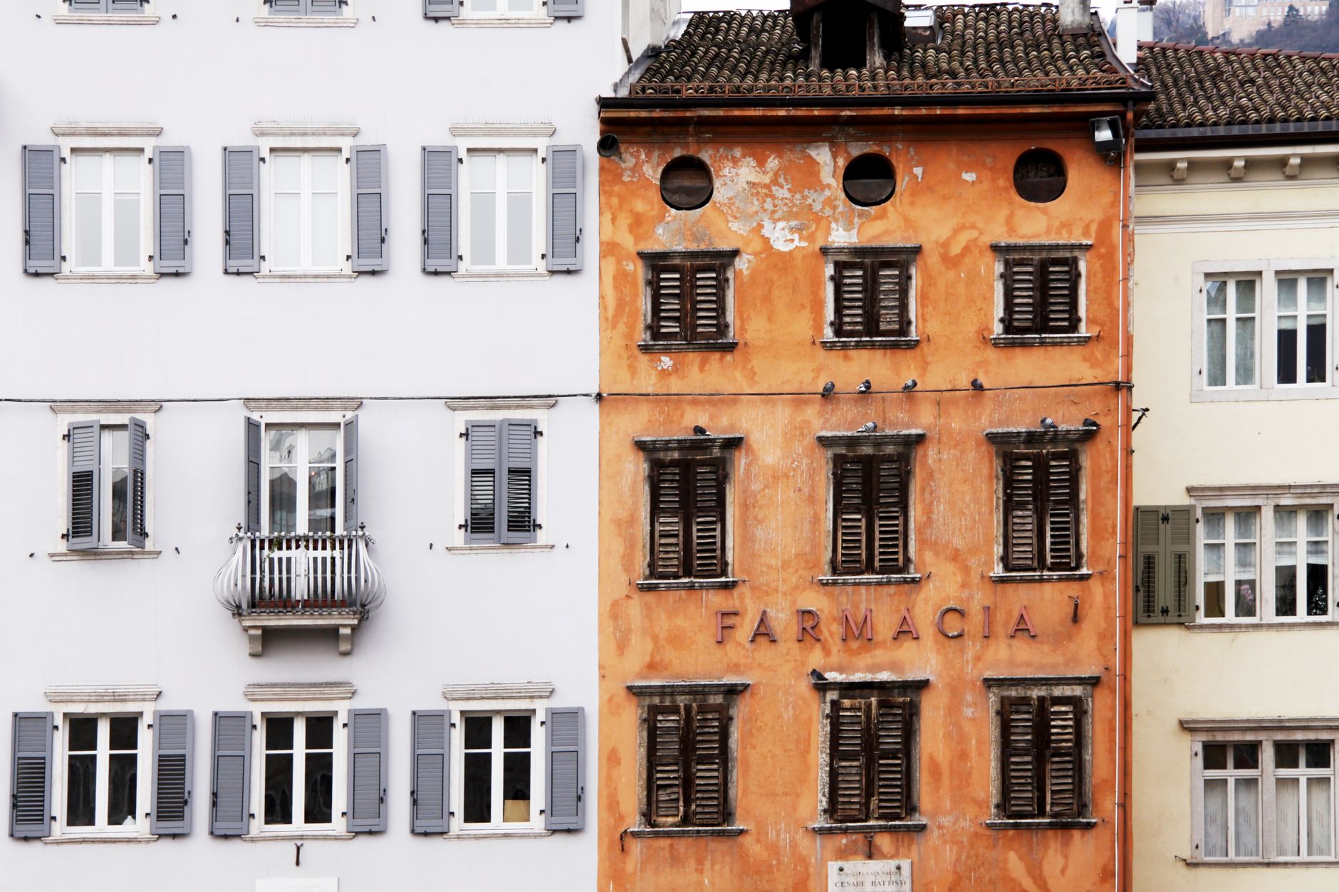 Colorful Italian building facades with rustic pharmacy storefront and classic window shutters.