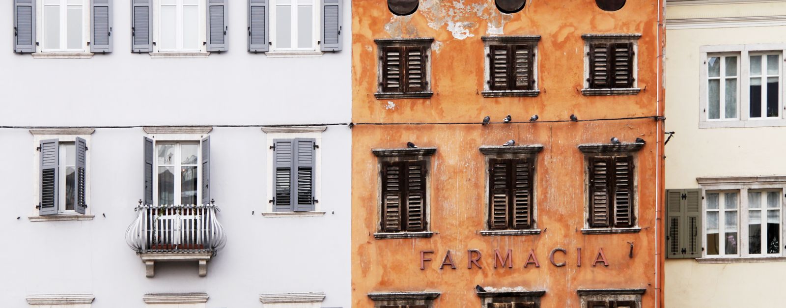 Colorful Italian building facades with rustic pharmacy storefront and classic window shutters.