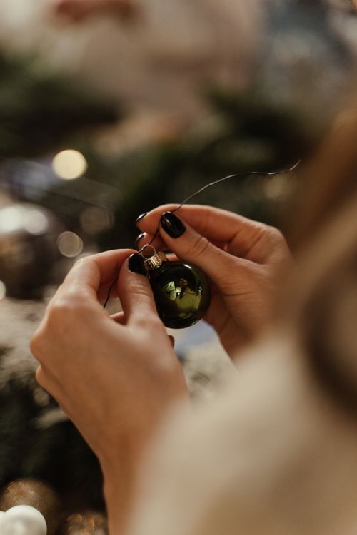Free Close-up of hands attaching a christmas ornament, evoking festive spirit indoors. Stock Photo