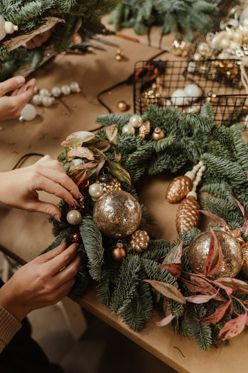 A Hand Putting Design on the Christmas Wreath