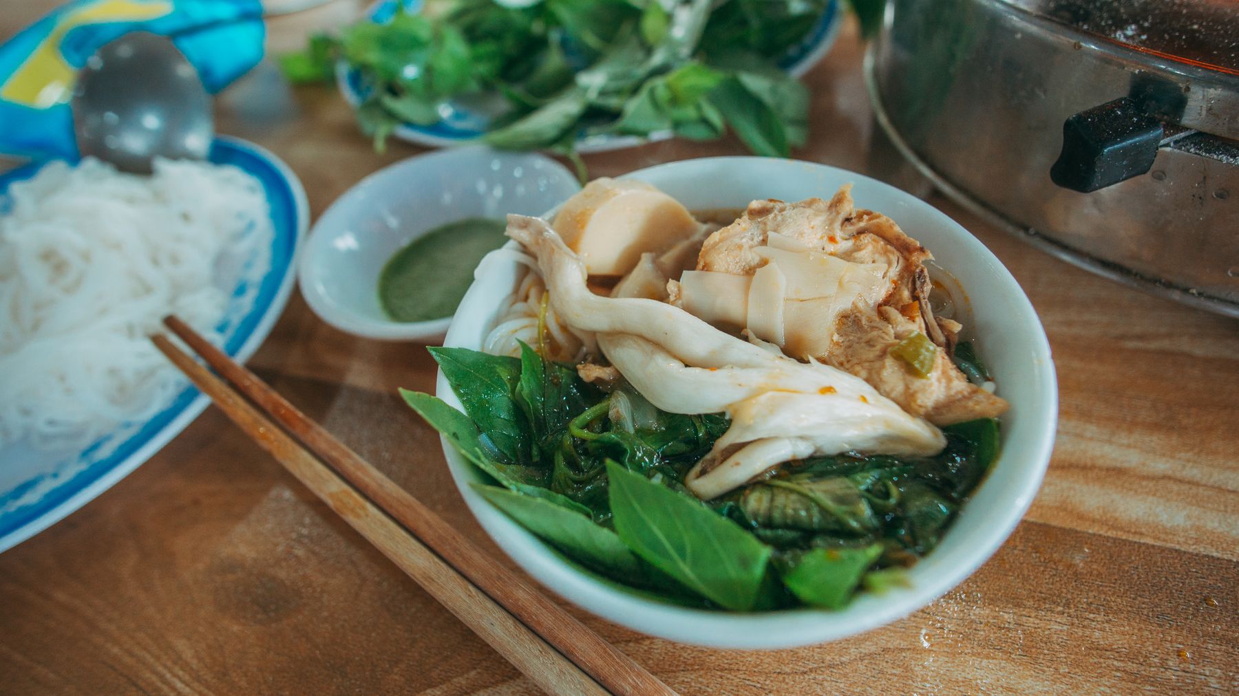 Savor the vibrant flavors of a Vietnamese soup bowl with fresh greens, herbs, and noodles.