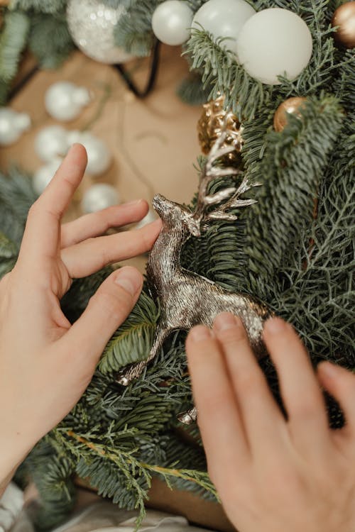 Person Placing a Deer Christmas Ornament on a Wreath