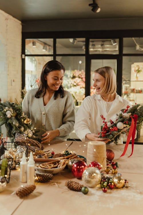 Two Women Smiling while Holding Christmas Wreaths