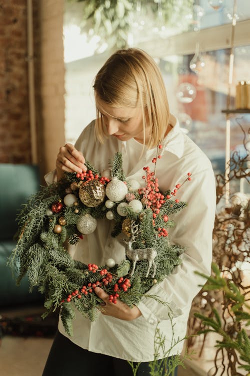 Woman in White Long Sleeve Shirt Holding a Wreath