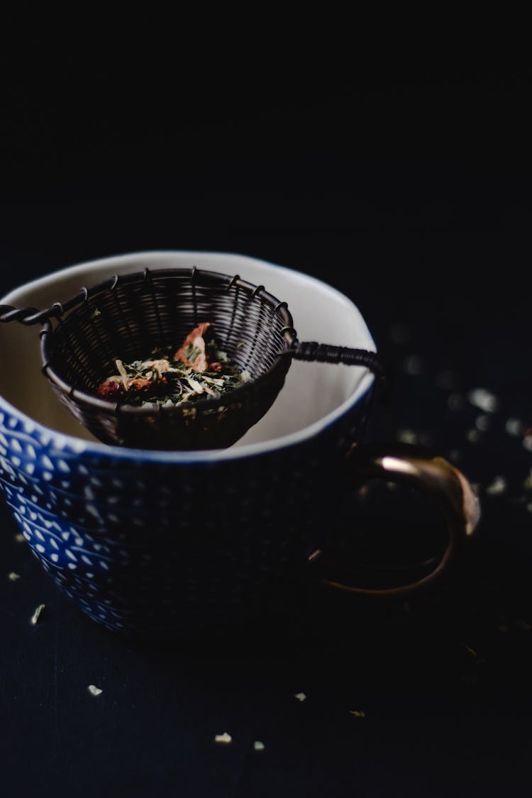 Black Sieve With Tea Leaves On A Blue Ceramic Cup