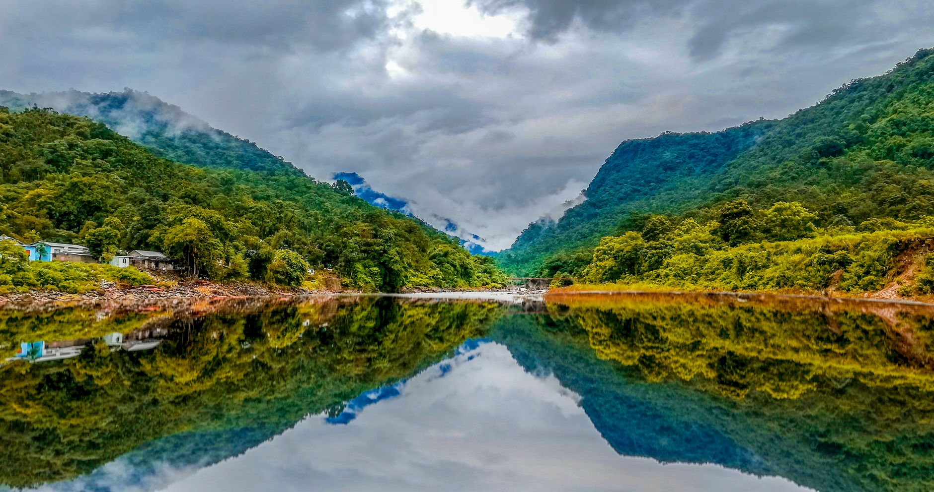 Tranquil lake reflection in East Khasi Hills, Meghalaya amidst lush greenery.