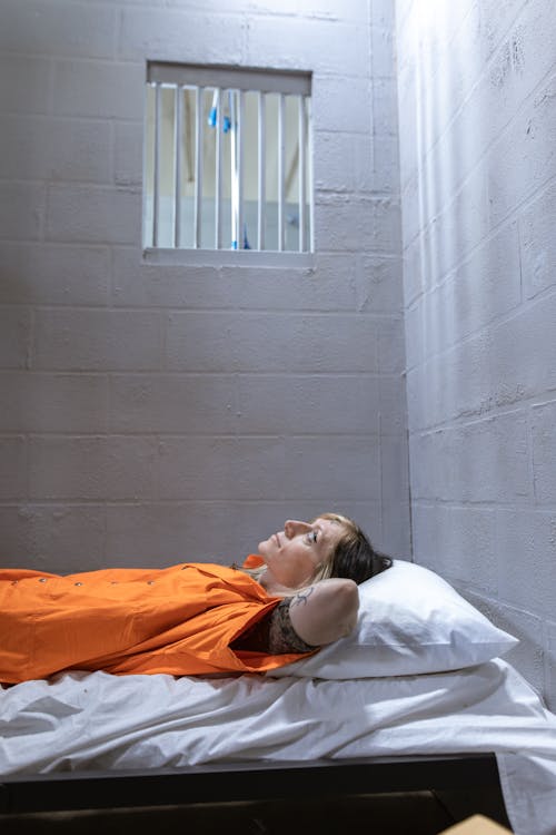 Free Woman in Prison Uniform Lying on Bed Stock Photo