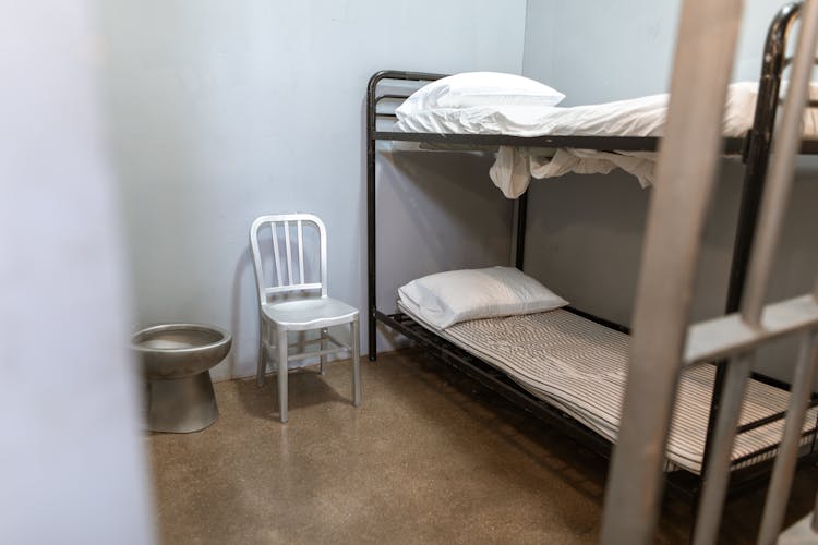 A Bunk Bed With Striped Foam Mattress In A Prison Cell