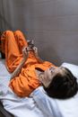 A Woman Wearing Prison Uniform Holding a Photo While Lying on Bed