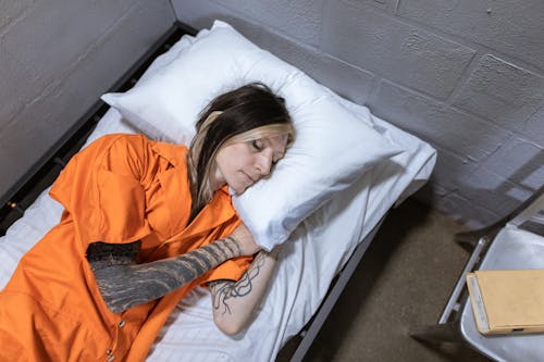 Woman in Orange Jacket Lying on Bed