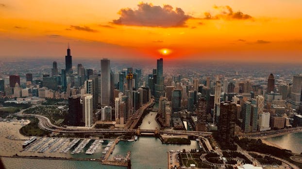 A breathtaking aerial view of Chicago skyline during sunset, showcasing skyscrapers and vibrant orange sky.