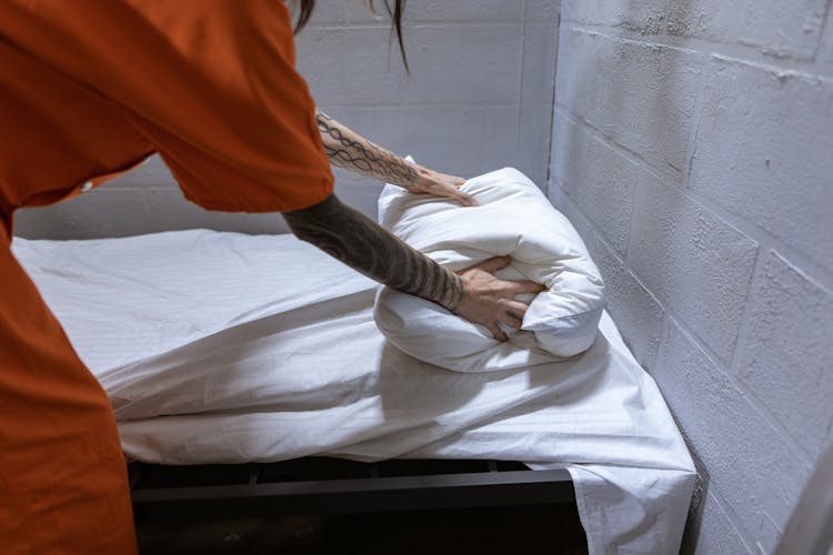 Person With Arm Tattoo Holding A White Pillow On Bed