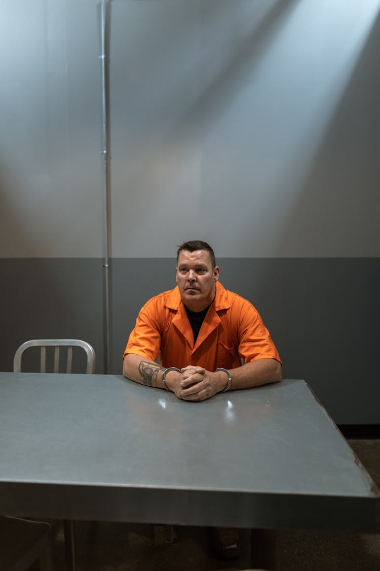 Man In Orange Shirt Sitting On Chair