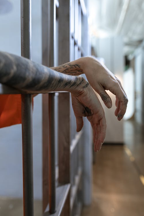 Hands of a Person Hanging from Steel Bars