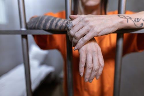 Free Hands of a Person with Tattoo Hanging from Steel Bars Stock Photo