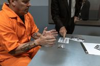 A Man in Prison Uniform with Handcuffs Sitting