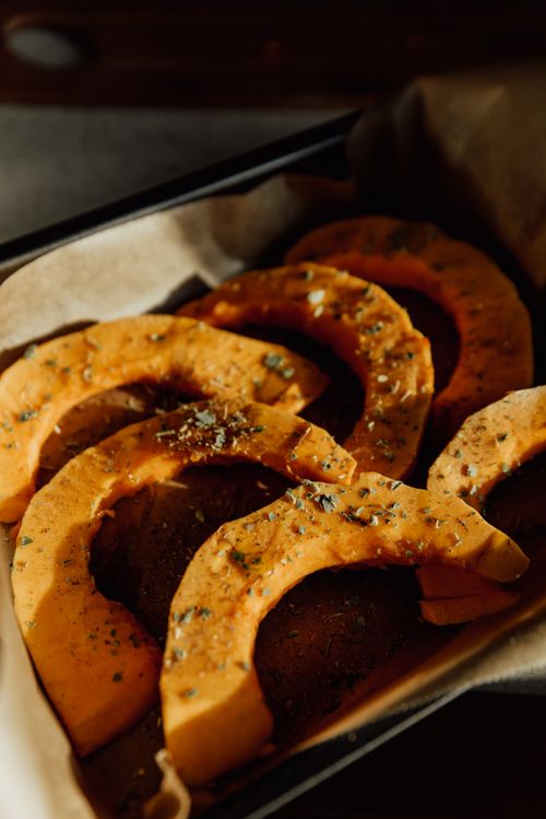 Free Golden roasted pumpkin slices seasoned with herbs in a baking dish. Stock Photo