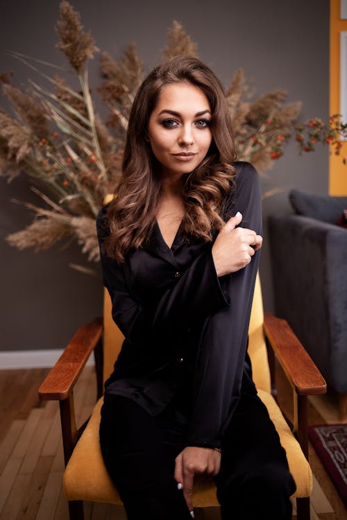 Gorgeous woman in silk blouse sitting on cozy armchair