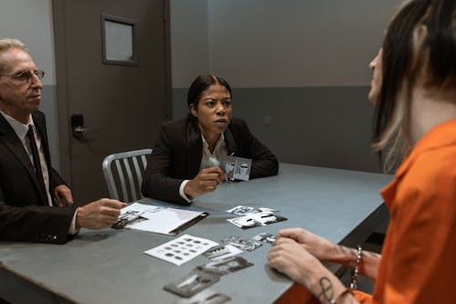 Woman in Black Jacket Sitting on Chair Interrogating an Inmate