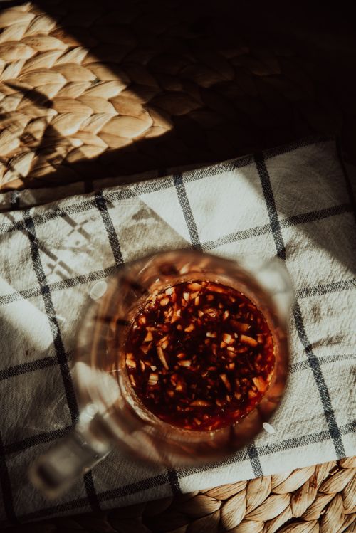 Free Aesthetic overhead view of a glass container with spicy soy sauce placed on a checkered cloth, casting warm shadows. Stock Photo