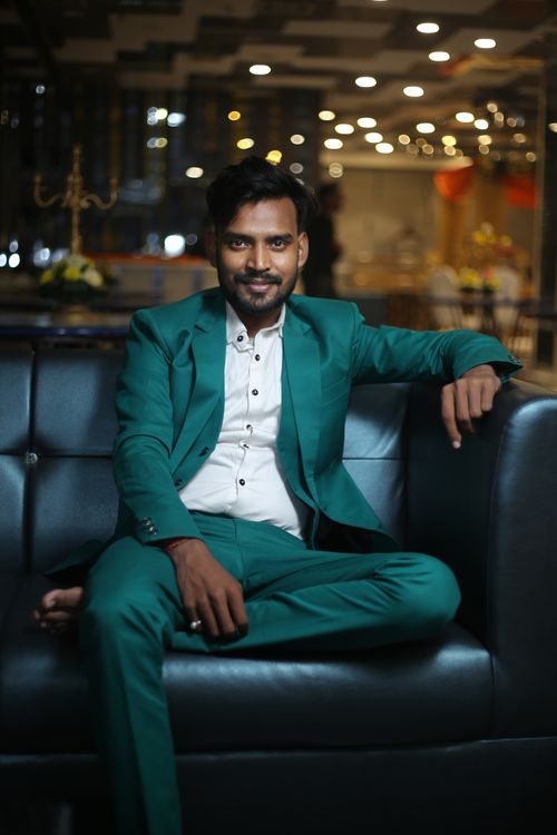 Free Confident ethnic barefoot male in elegant suit sitting on leather sofa and looking at camera Stock Photo
